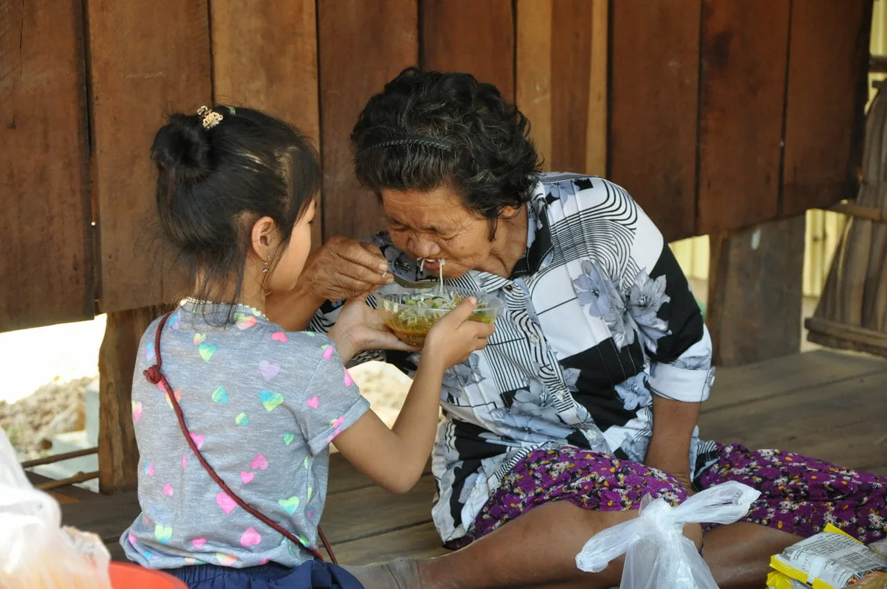 Sreykeo helping to feed one of the elderly - Cambodia